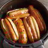 A pot of hot dogs in a fryer.