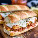 A chicken parmesan sandwich on a wooden table.
