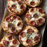 Homemade pizza bagels on a wooden board.