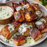 A bowl of salmon bites with a white sauce.