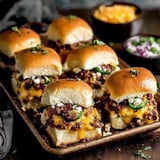 A tray of cowboy sliders with cheese and jalapenos.
