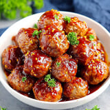 A bowl of meatballs covered in a sweet and spicy sauce.