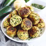 A plate of zucchini balls with a green vegetable on the side.