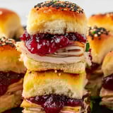A stack of turkey sliders with jelly and black seeds.