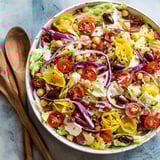 A bowl of salad with tomatoes, lettuce, chickpeas, and red onions.