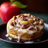 A plate with a cinnamon roll and an apple.