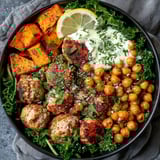 A bowl of food with meatballs, chicken, and vegetables.