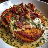 A plate of country fried pork chops with bacon gravy.