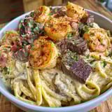 A bowl of Cajun Shrimp and Steak Alfredo Pasta.