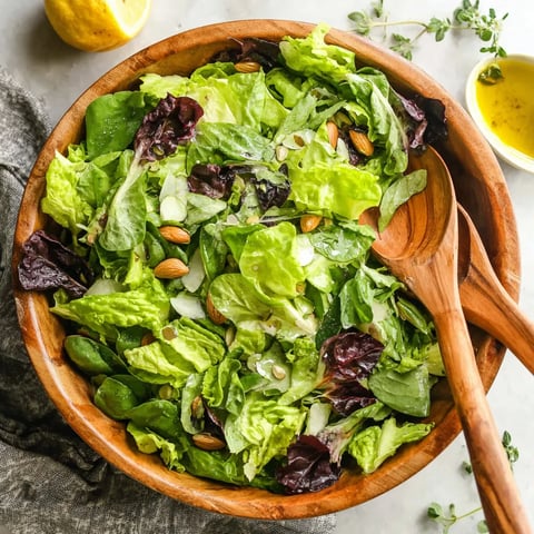 A wooden bowl filled with a green salad.