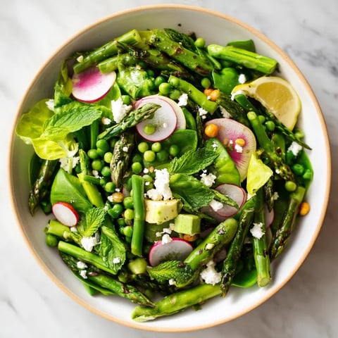 A bowl of fresh vegetables, including asparagus, peas, and radishes, is served in a white bowl.